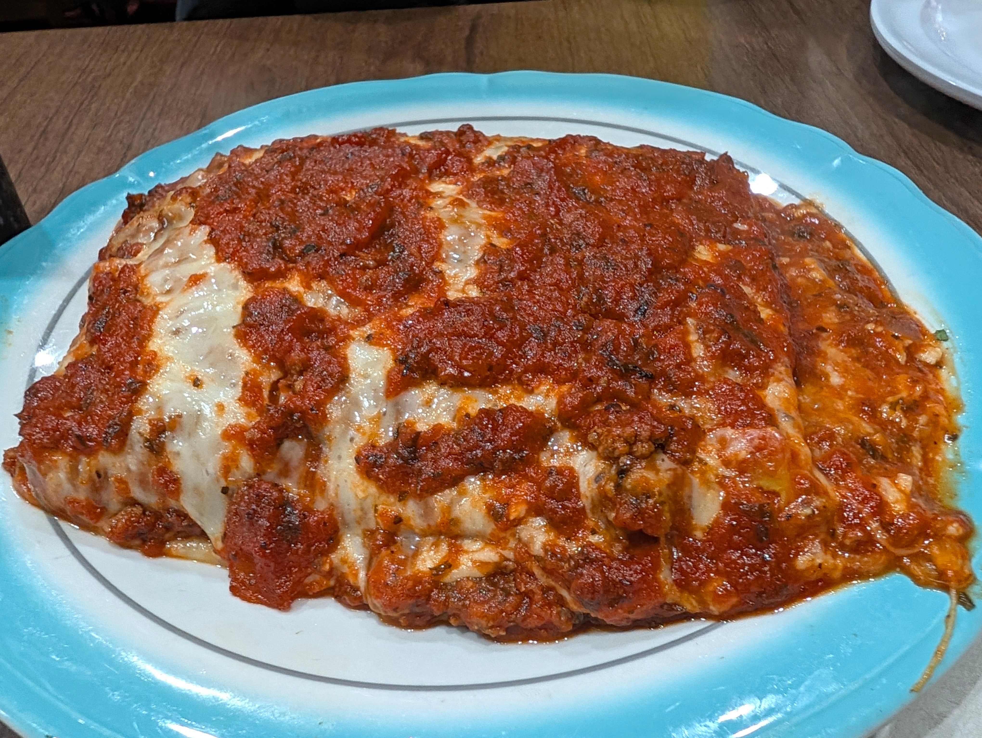 Lasagna covered in meat sauce and melted cheese on a blue-rimmed plate