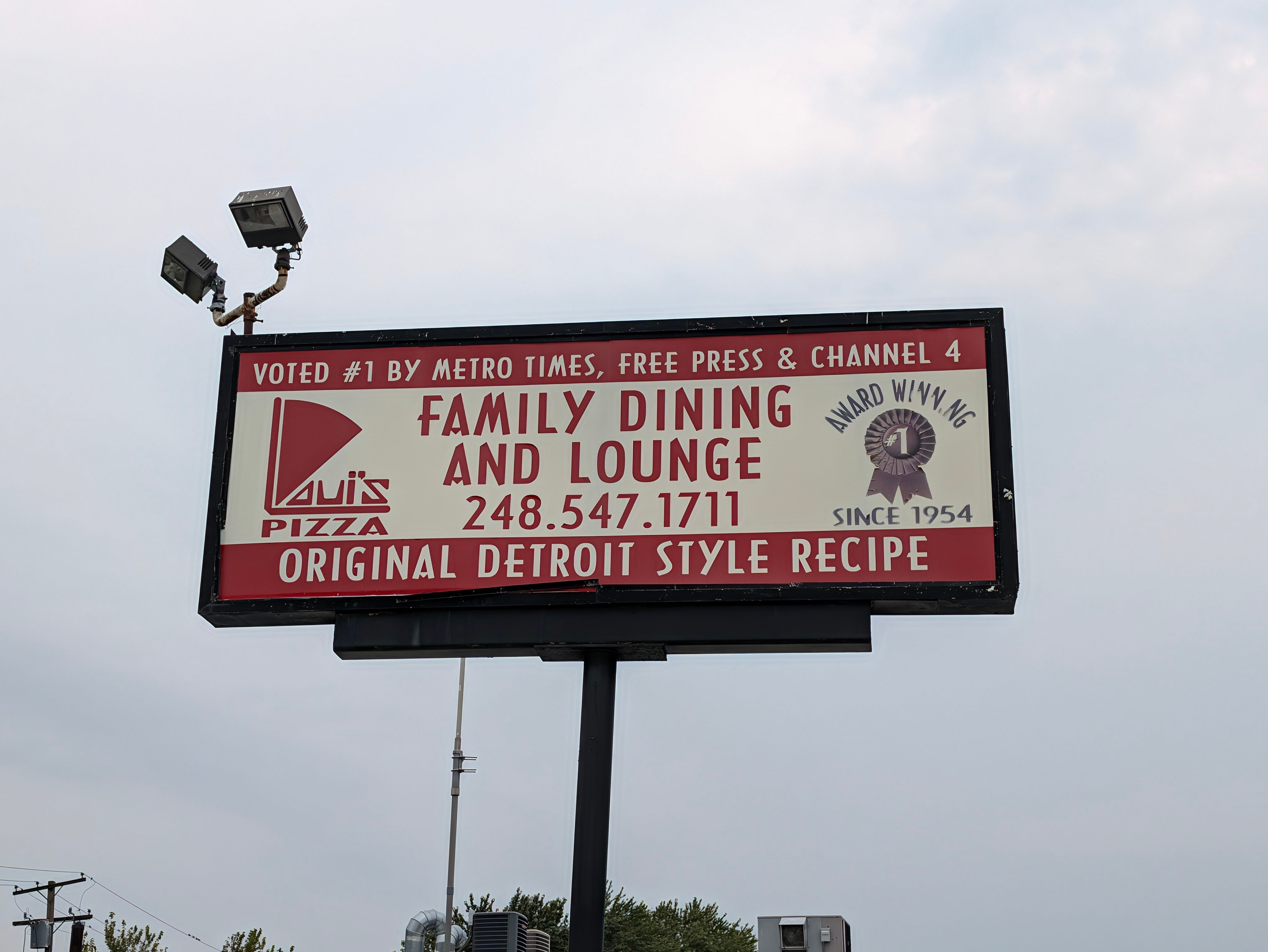 Roadside sign for Loui's Pizza reading Family Dining and Lounge, Original Detroit Style Recipe, Since 1954